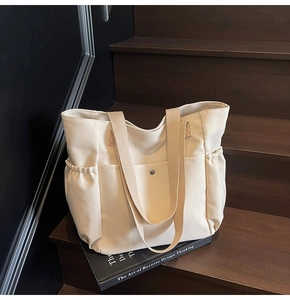 Detailed view of cream canvas tote bag with snap front pocket on wooden stairs