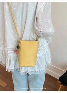Detail of yellow lychee leather mini tote bag with cute cherry charm and brand logo