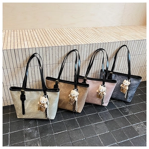 Detail view of four embossed tote bags in pastel colors with bear charms and gold buckles