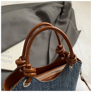 Close-up of denim bucket bag with brown leather handles and knotted strap details