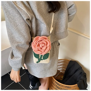 Gros plan du petit sac bandoulière au crochet avec une fleur rose en relief et feuille