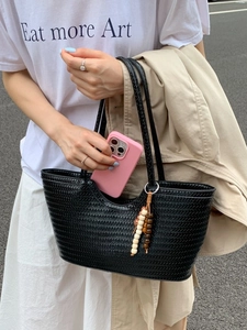 Black woven tote bag with wooden bead charm and dual handles for a summer casual look