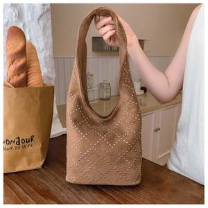 Detail of brown suede tote bag with silver metal studs in a diamond lattice pattern