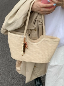 Chic beige woven tote bag with wavy rim and wooden bead charm accessory