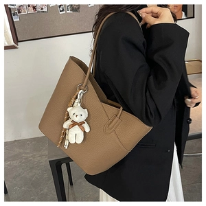 Brown litchi grain tote bag with bear charm shown on model in a professional office setting