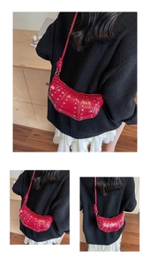 Close-up of red patent leather punk style crossbody bag with silver metal rivets detail