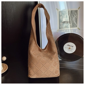 Detail of a brown suede hobo bag featuring silver rivets arranged in a diamond pattern