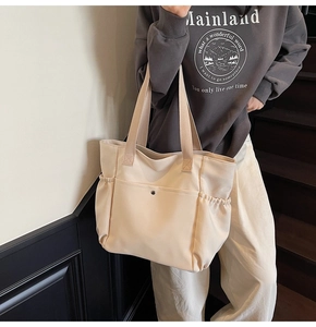 Detail of cream canvas tote bag with magnetic flap pocket and side pleated elastic pockets