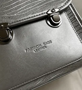 Detail shot of silver leather bag showing wavy stitching and dark metal buckle