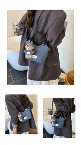 Detail of dark blue denim bucket bag featuring twin round handles and a bear charm