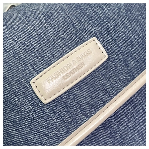 Detail of dark blue denim fabric with a beige leather label showing Fashion logo