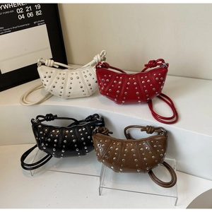 Detail of four crescent rivet bags in white, red, black, and tan on display