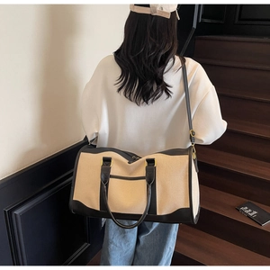 Close-up of contrast trim canvas travel bag with adjustable strap and gold hardware