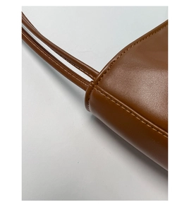 Detail einer braunen Leder-Eimertasche mit feinen Nähten und glatter Schultergurt-Textur