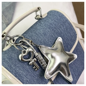 Detail of blue denim backpack with white leather trim and silver Y2K star pendant