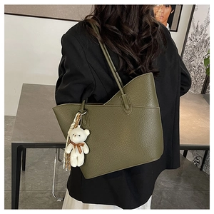Detail of olive green leather tote bag with lychee texture and plush bear charm
