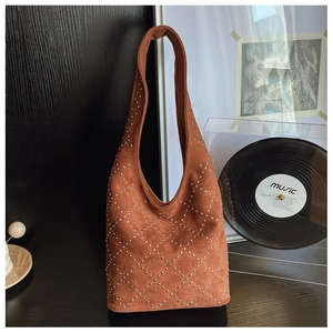 Close-up of brown suede hobo bag with silver metal rivets in a retro interior setting