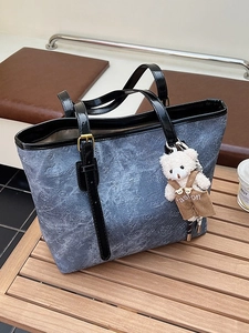 Vintage denim blue tote bag with cartoon bear embossing and plush charm on wood table