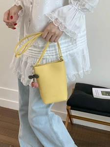 Chic bright yellow leather bucket bag with cherry charm and elegant crossbody strap