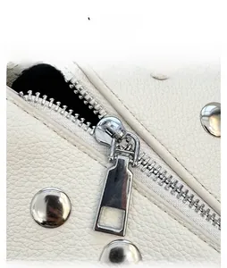 Detail shot of smooth silver zipper and rivets on white lychee grain leather handbag