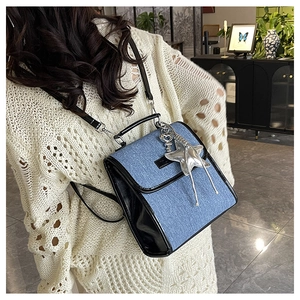 Detail of denim shoulder bag with black leather trim and silver star pendant accessory
