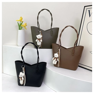 Close-up of three textured bucket bags in black, brown and dark green with bear charms