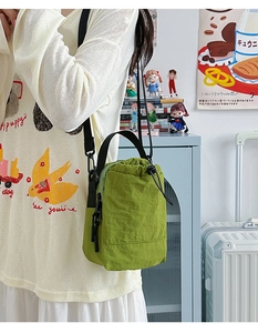 Detail of green nylon drawstring bucket bag with adjustable strap and waterproof fabric texture