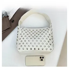 Size comparison of white studded leather handbag next to a smartphone device