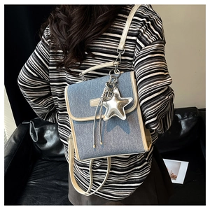 Blue denim mini backpack on model's back with silver star charm and fashion label