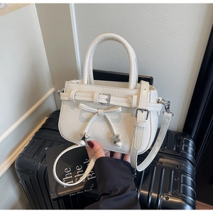 Détail du sac à bandoulière crème avec boucle et clous étoiles sur une malle vintage