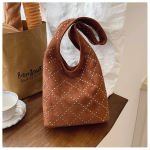 Detail view of brown suede hobo bag with silver rivets in a chic lifestyle setting