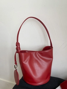 Minimalistische rote Beuteltasche aus Leder mit geflochtenem Knotengurt und Anhänger