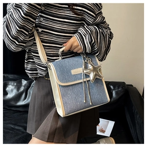 Detail of denim and white leather patchwork bag featuring a silver star pendant