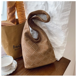 Close-up of brown suede hobo bag with silver rivets in a stylish cafe setting