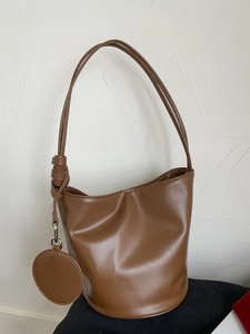 Minimalistische braune Beuteltasche aus PU-Leder mit geknotetem Gurt und rundem Anhänger