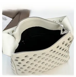 Detail view of the white studded handbag featuring silver rivets and zipper closure