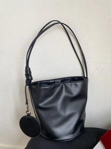 Minimalistische schwarze Beuteltasche mit Schultergurten und rundem Münzanhänger