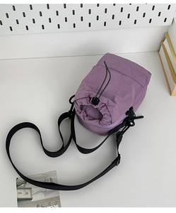 Close-up of purple nylon drawstring crossbody bag with adjustable strap on desk