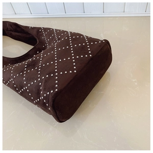 Detail view of coffee suede shoulder bag with metallic stud rivets in a diamond pattern