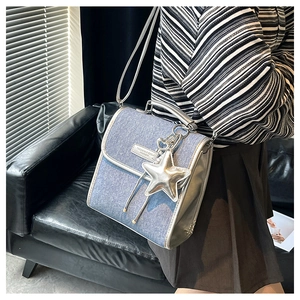 Detail of blue denim square bag with silver metallic trim and star pendant accessory