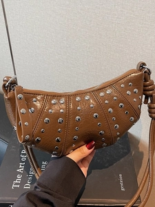 Brown croissant shoulder bag with silver studs and sleek glossy leather finish