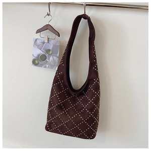 Close-up of dark brown suede shoulder bag featuring silver rivets in a diamond pattern