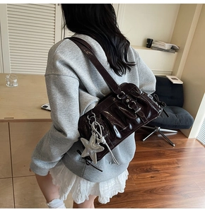 Detail of dark mahogany patent leather shoulder bag with glossy finish and star charm