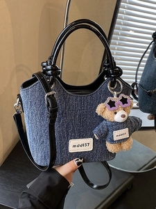 Contrast denim bucket bag with leather handles and a plush bear pendant accessory