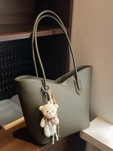 Minimalist olive green pebble leather bucket bag with cute plush bear keychain accessory