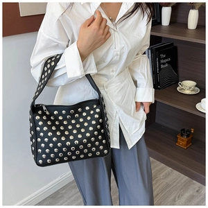 Detailed shot of black pebbled leather texture and silver metal rivets on the handbag