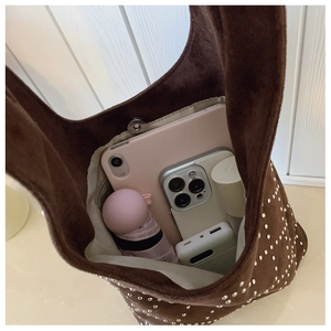Top view of spacious interior of brown studded tote bag showing tablet and daily essentials