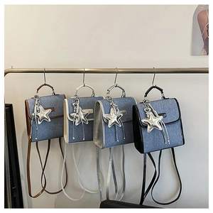 Detail of four mini denim backpacks featuring star charms and colorful leather piping