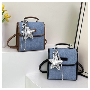 Detail of small denim backpacks with leather trim and star charms on white display