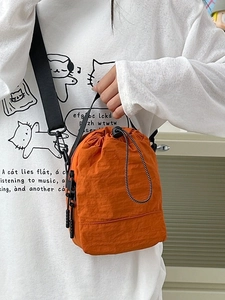 Orange nylon crossbody phone bag with drawstring closure and adjustable black strap